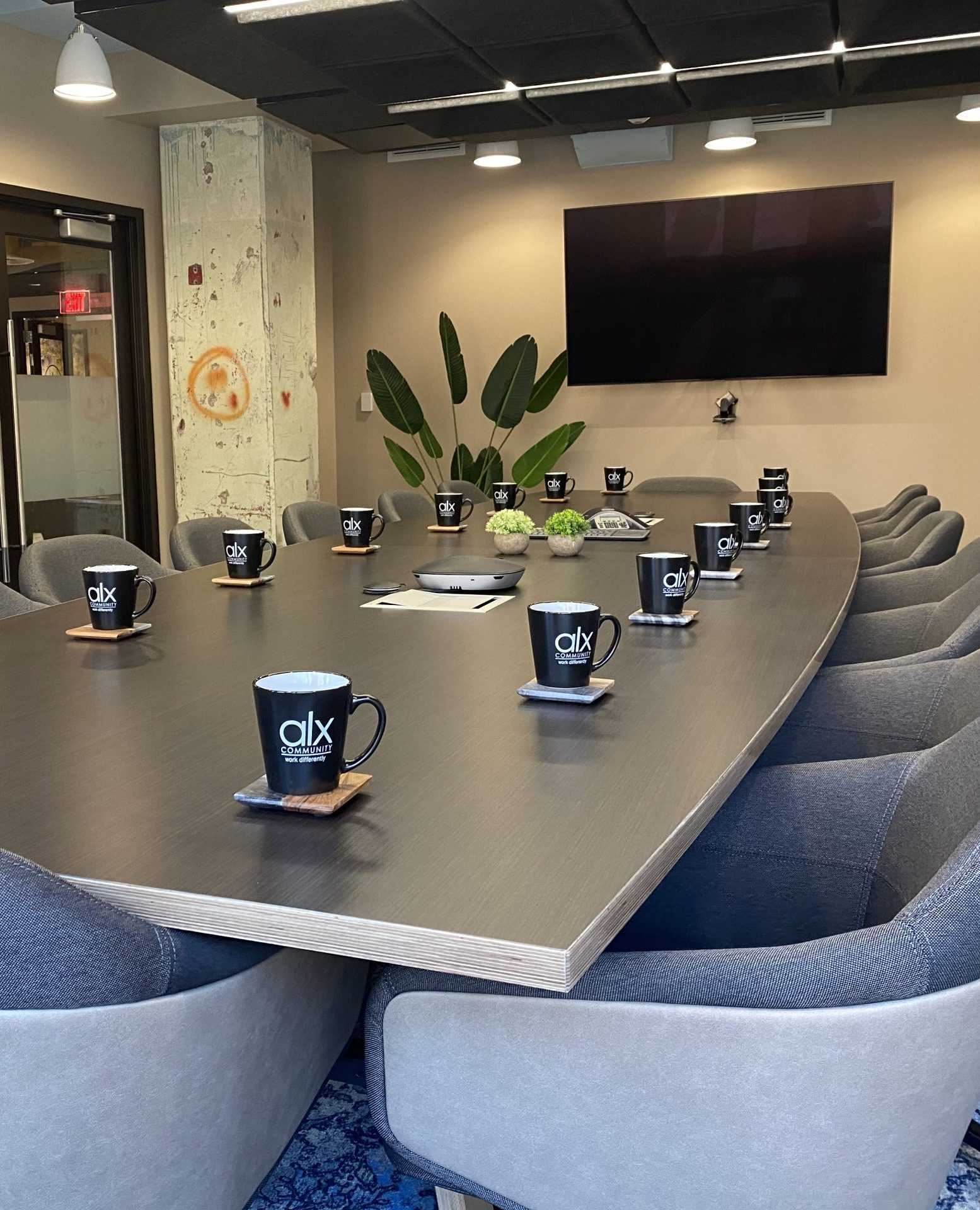 image of a modern conference room with a long boardroom-style conference table and comfy chairs.